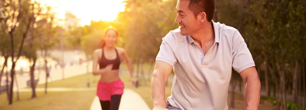 Man riding a bike while women runs behind him
