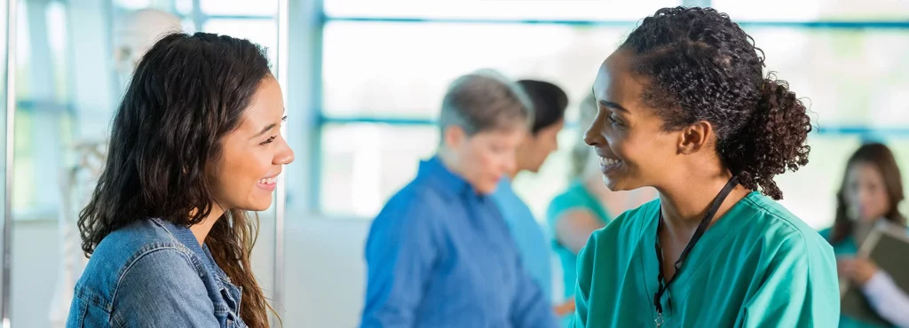 Young woman and young nurse speaking with each other while smiling