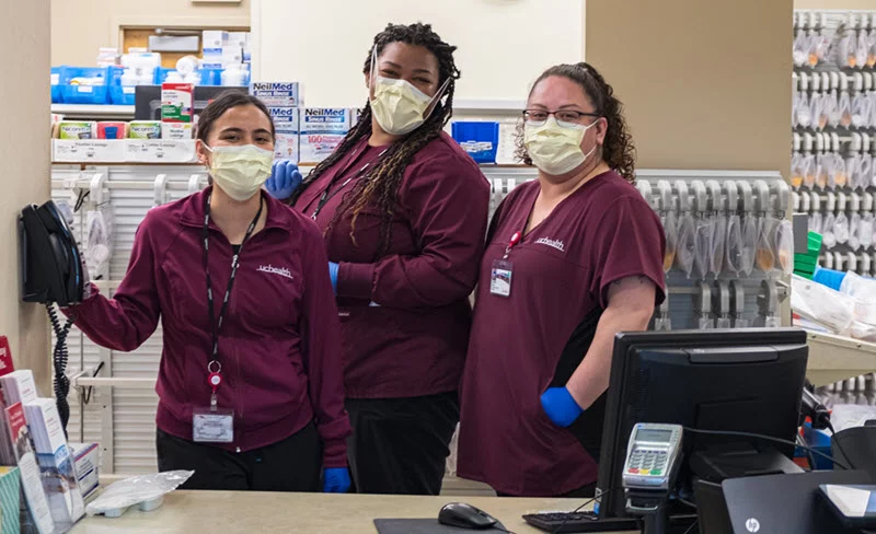 Three masked UCHealth staff behind a counter