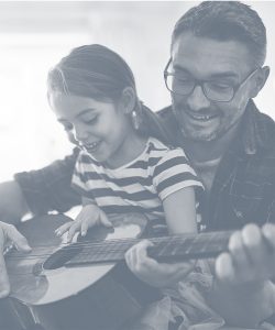 Father and young daughter playing guitar