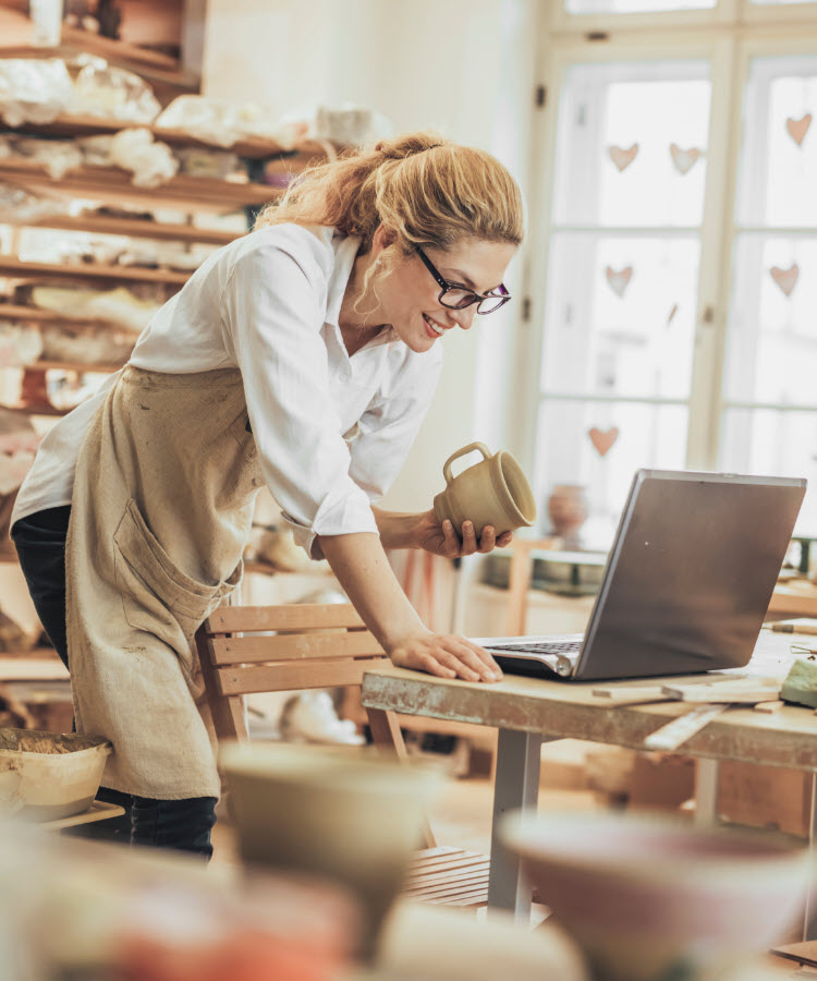 Woman looking at laptop in pottery studio