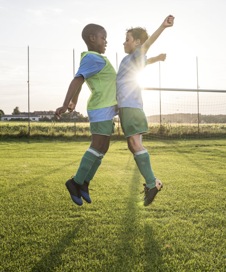 Two boys jumping in celebration on the soccer field