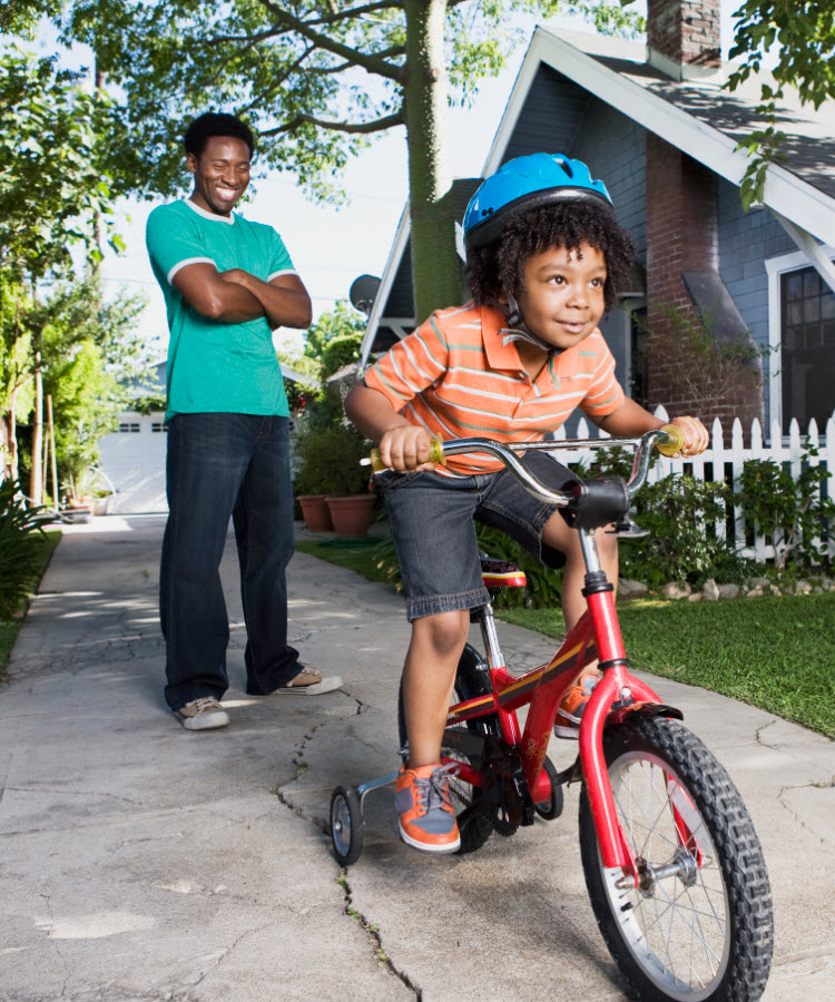 Father teaching son to ride bicycle