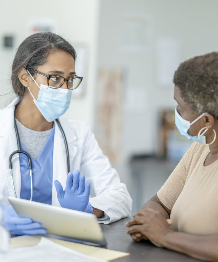 Female doctor consulting with older woman patient