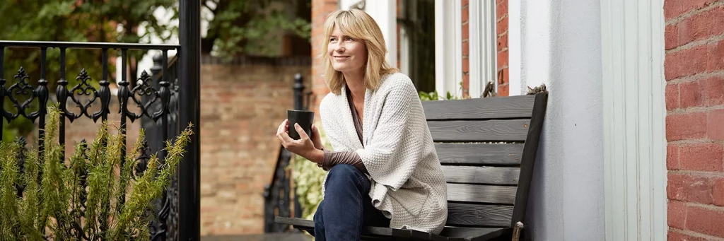 UCHealth Developing the future of medicine. Woman drinking coffee on park bench.