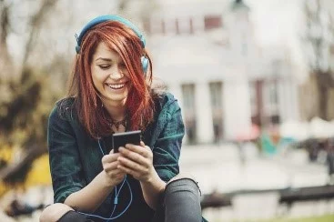UCHealth Healthy Hearts and Minds vaping page. Teen girl listening to music with headphones outside of school.