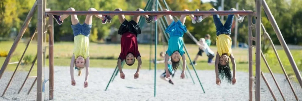 UCHealth Healthy Hearts and Minds Healthy Kids Healthy Start kids hanging upside down from monkey bars.