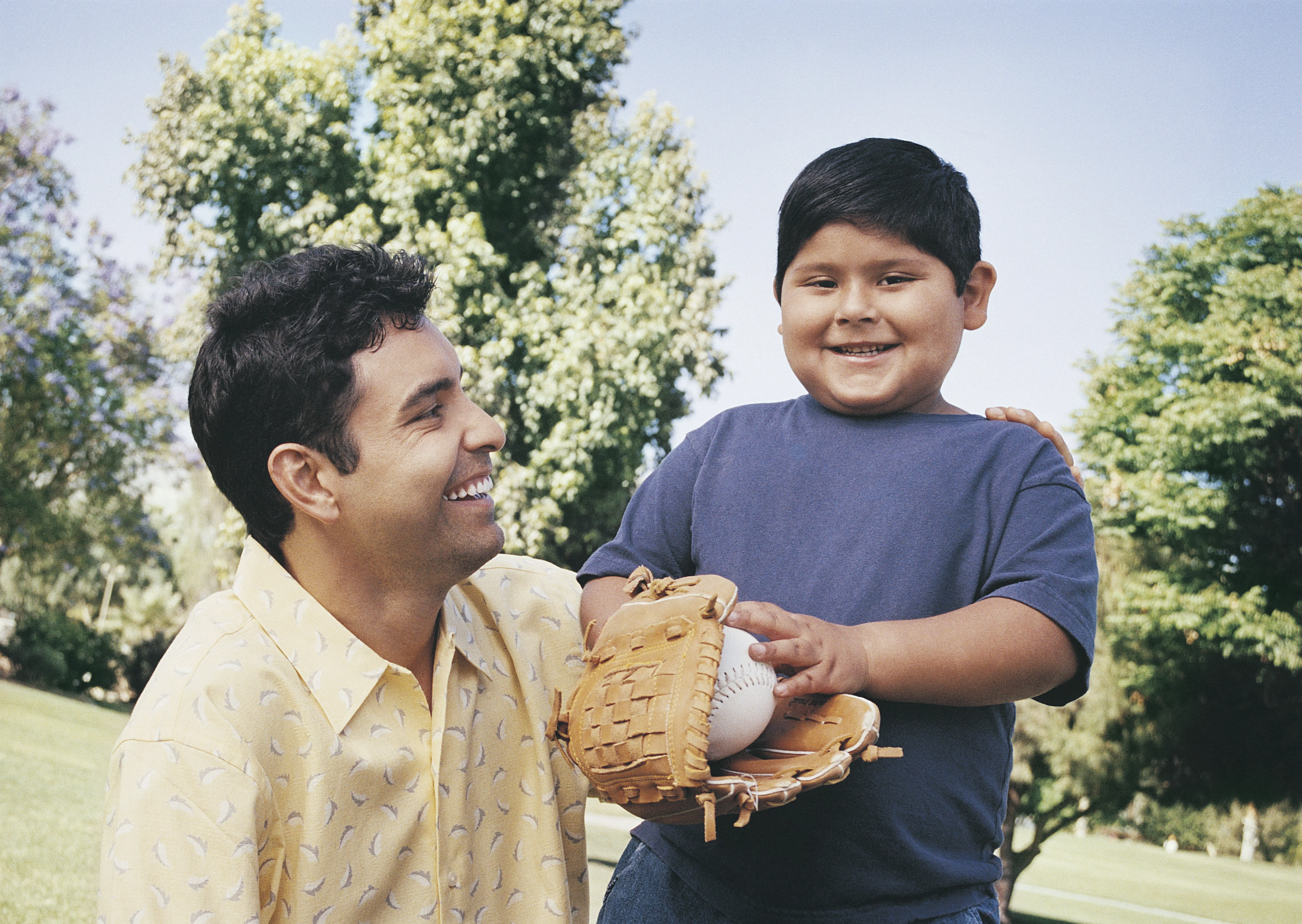 UCHealth Healthy Hearts and Minds Family Program. Father and son with baseball glove and ball at park.
