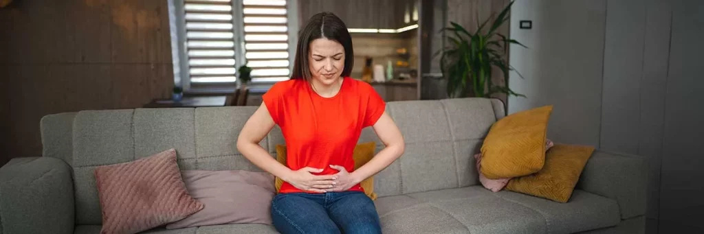UCHealth woman on couch clutching stomach in pain