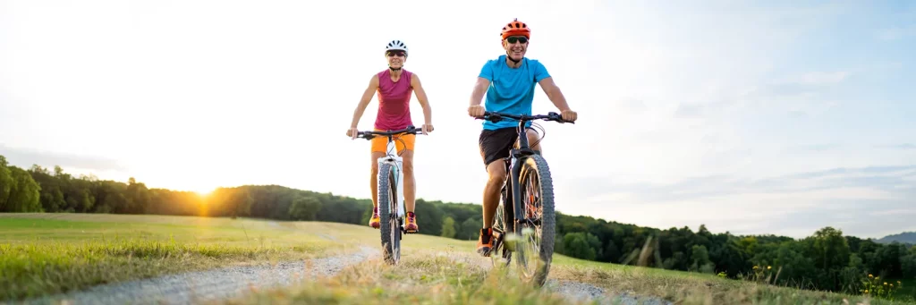 Transplante de hígado UCHalth. Pareja mayor montando en bici al atardecer.