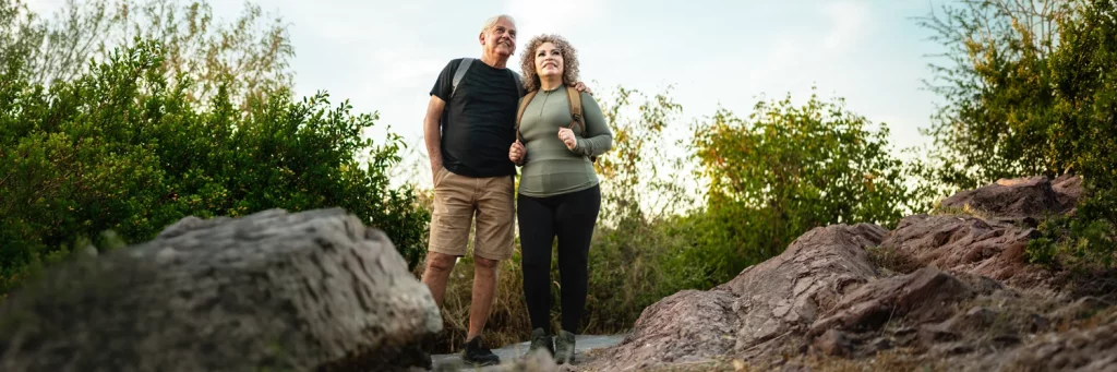 UCHealth kidney and pancreas transplant. Older couple hiking on a rock outcropping.