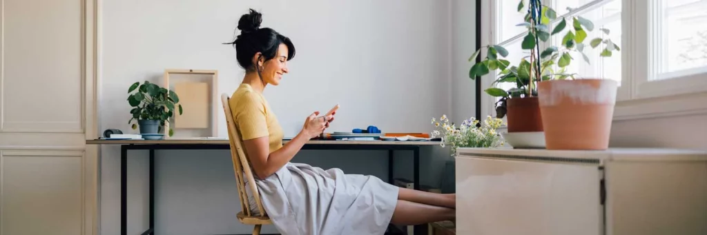 UCHealth Virtual Primary Care woman at desk chatting on cell phone.