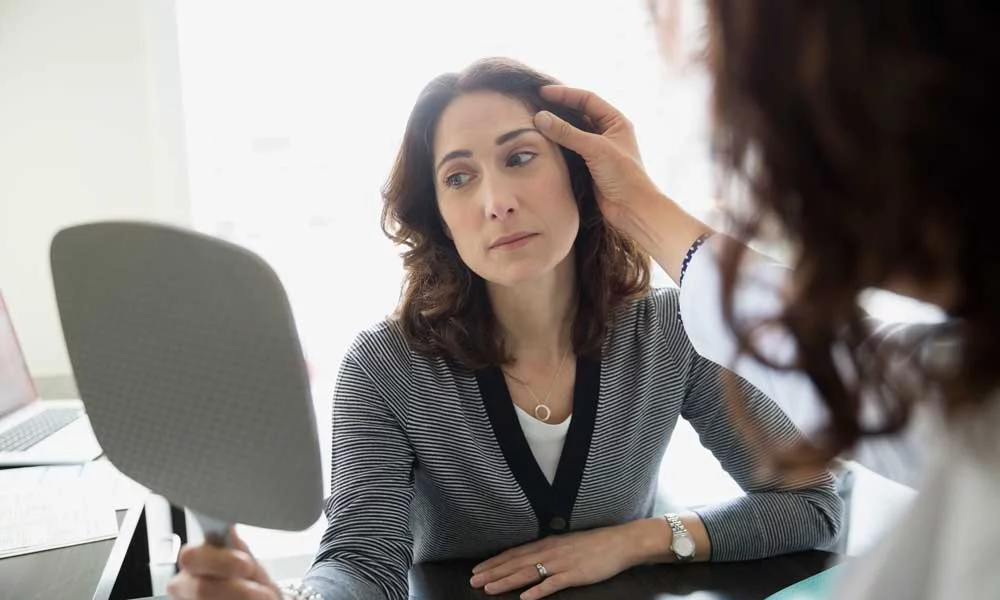 UCHealth Aesthetic Brow Pstosis, woman looking in mirror, consulting with provider. 