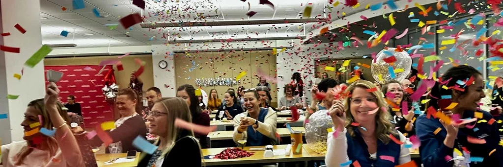 UCHealth MCR awarded 4th ANCC Magnet designation. Group of nurses in meeting room with confetti falling down.