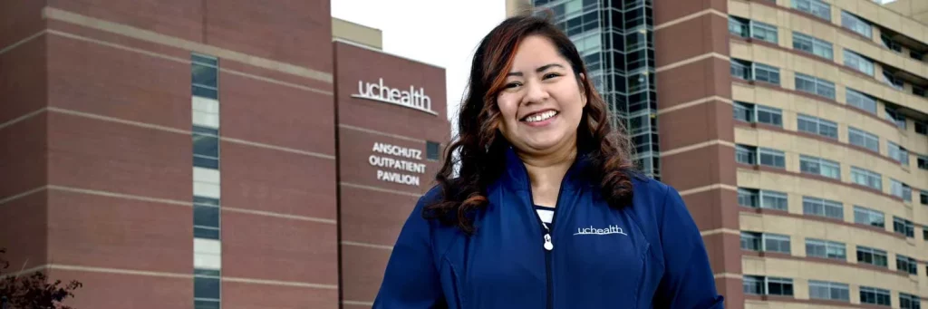 UCHealth nurse led care coordination to enhance the infusion clinic experience. Nurse standing in front of the UCHealth Anschutz Outpatient Pavilion.