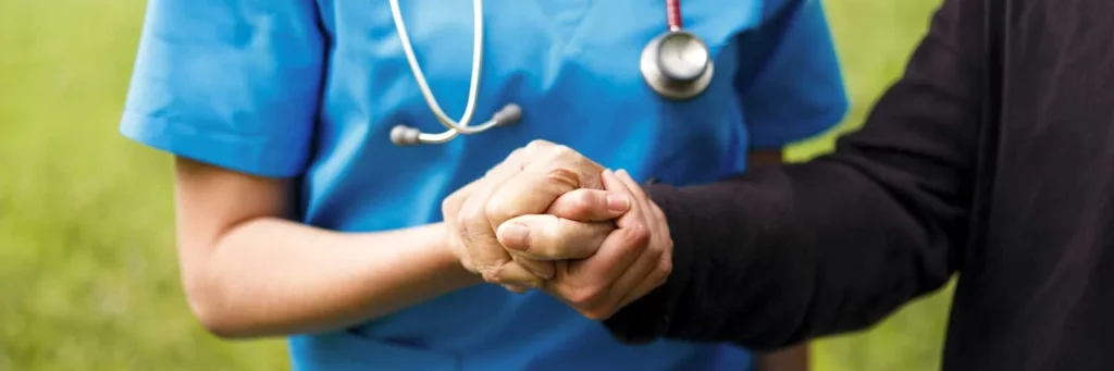 UCHealth offering follow up care for patients who experience violence. Patient and nurse holding hands.