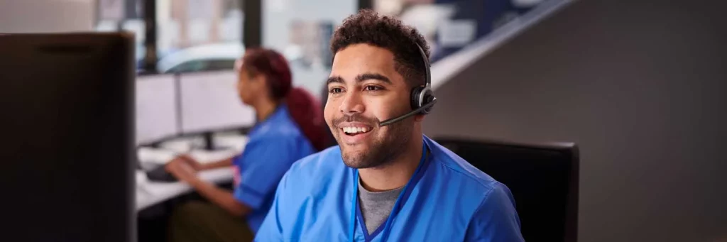 UCHealth expanding the after hours call services for patients. Nurse sitting at desk with headset on and smiling.