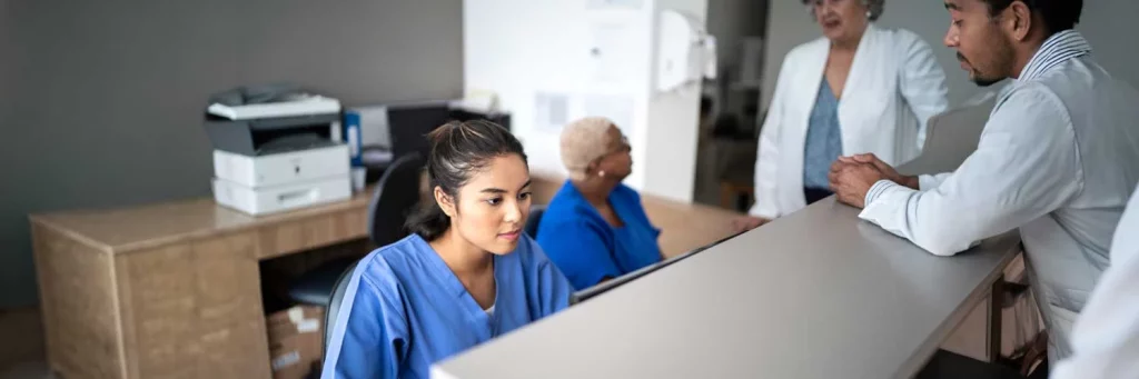 UCHealth centralized sitter model supports patient safety. Nurse in office setting working on computer.