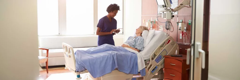 UCHealth ICU diaries improve ICU patients experience. Patient standing next to patient bed and talking with patient.