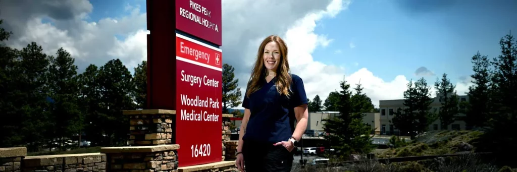 UCHealth helping patients return home sooner after ED visits. Nurse standing in front of Poudre Valley emergency entrance sign.