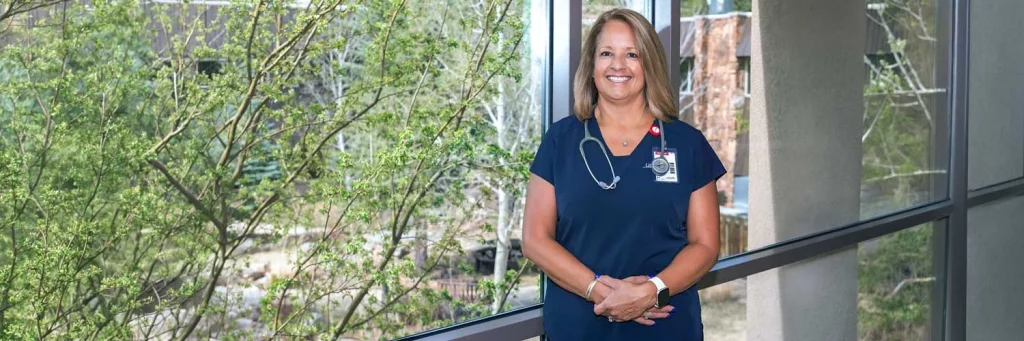 UCHealth Managing the balancing act while leading through transformation. Nurse standing in front of window in hospital.