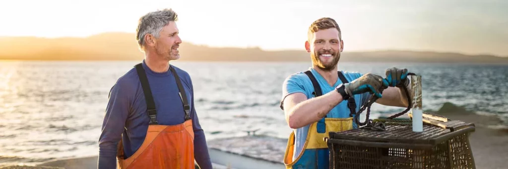 Neuro-optología UCHealth, dos hombres levantando una trampa de langosta en un barco en el océano.