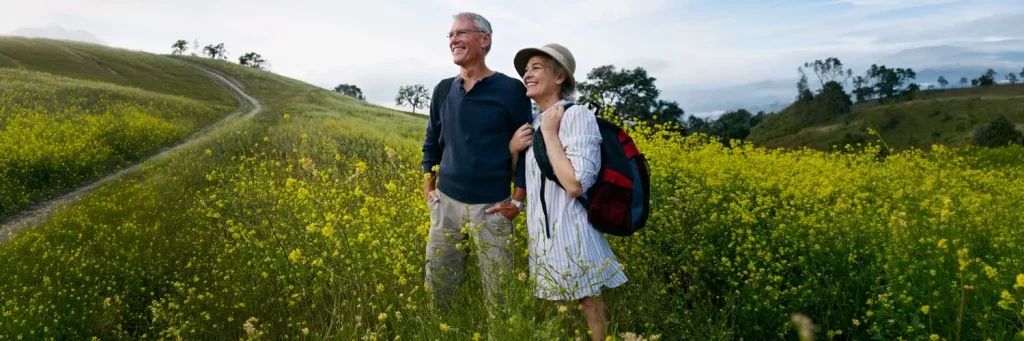 UCHealth comprehensive eye care. Couple hiking in field of wildflowers.