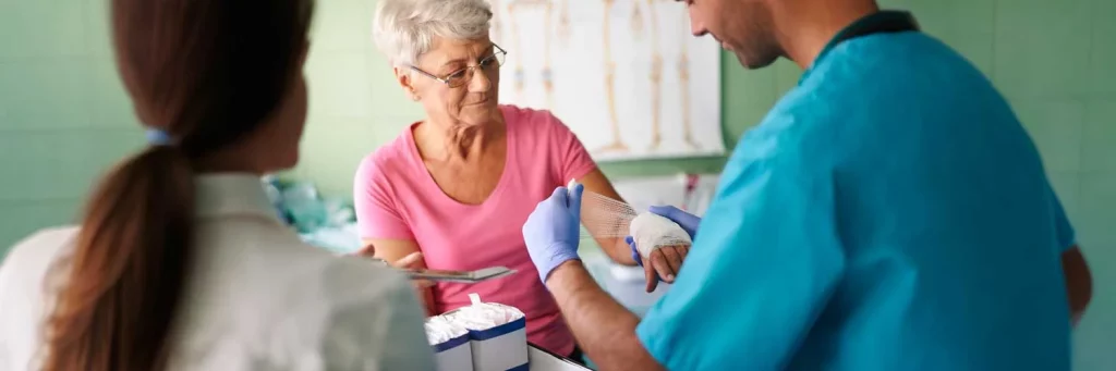 UCHealth burn care, nurse changing burn dressing on elderly woman.