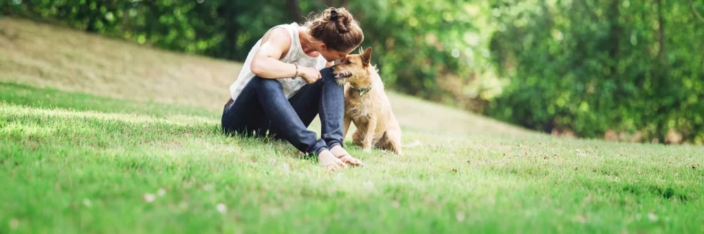 UCHealth Metro Denver cancer support page. Woman sitting with dog in park.