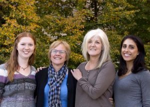 Four women who are working to prevent skin cancer pose side by side in front of a tree.