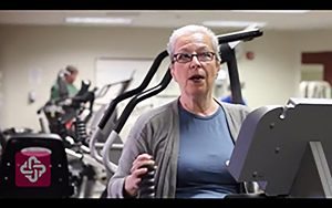 An oncology patient works on a machine during physical therapy.