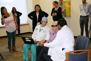 bionic eye patient sits with his doctors.
