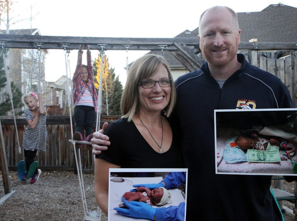 Steve Armstrong (right) and his wife, Melissa, hold up photos of their girls who were born prematurely at Poudre Valley Hospital. The girls, Maya (back right), now 11, and Sofia (back left), 8, are happy, healthy kids. Photo by Kati Blocker, UCHealth.
