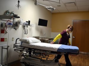 technician sets a patient bed in a dark and empty ER.