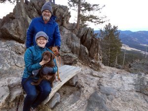 Bill and his wife holding the dog on top of a ridge.