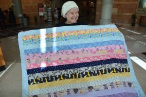women holds up a quilt