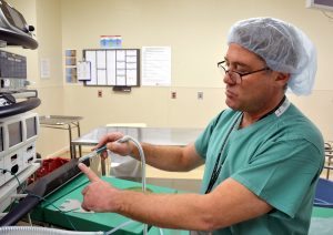 In this photo, Chris Lolley, OR charge nurse at UCH, points to the plastic tube that fits over the tip of an electrosurgery device, evacuating surgical smoke.