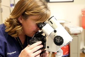 Elyse Diewald, coordinator of the UCHealth sexual assault program called SANE looks in a piece of equipment called a colposcope which is used to collect evidence after a sexual assualt.