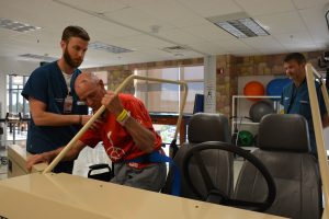 Patrick Buxton transfers from a wheelchair to a simulated car, a gift of the Memorial Hospital Foundation. Occupational therapist Andrew Bettlach, assists. Gregory Braeger, therapy manager, said that allowing patients to practice getting in and out of a car may help prevent falls.