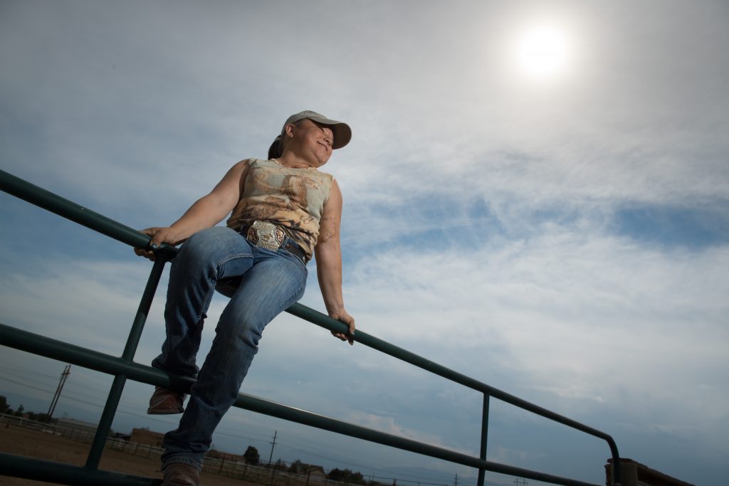 Sara Millard sits on a fence while taking a break from training for her rodeo event.