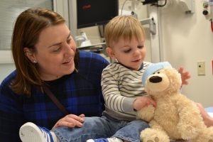 Ethan Bell reaches over to hug his teddy bear after a quick visit with the doctor during a recent Teddy Bear Hospital event at UCHealth Poudre Valley Hospital in Fort Collins