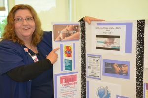 Carol Lawson, a nurse at UCHealth Memorial Hospital, is shown next to a display about postpartum depression.