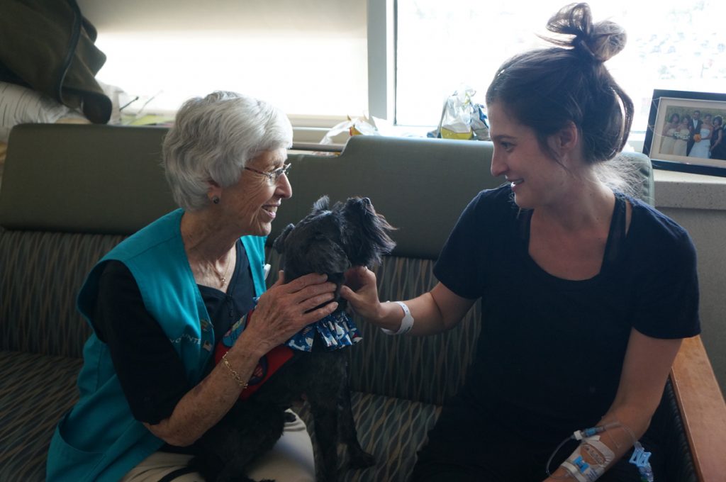 Marta, a therapy dog at University of Colorado Hospital, and her owner, Louella Stoever, visit with patient Kate Buffington.