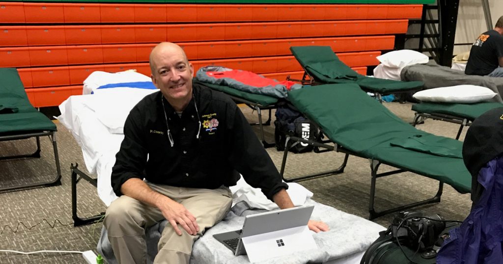 Pat Conroy, an emergency volunteer, sleeps on a cot on a basketball court after heading to Florida to help with hurricane recovery.