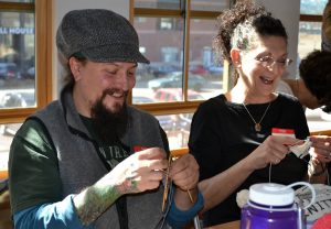 Dustin Nature Duvall of Fort Collins and Diane Volpe of Loveland share a laugh as they create knitted knockers.