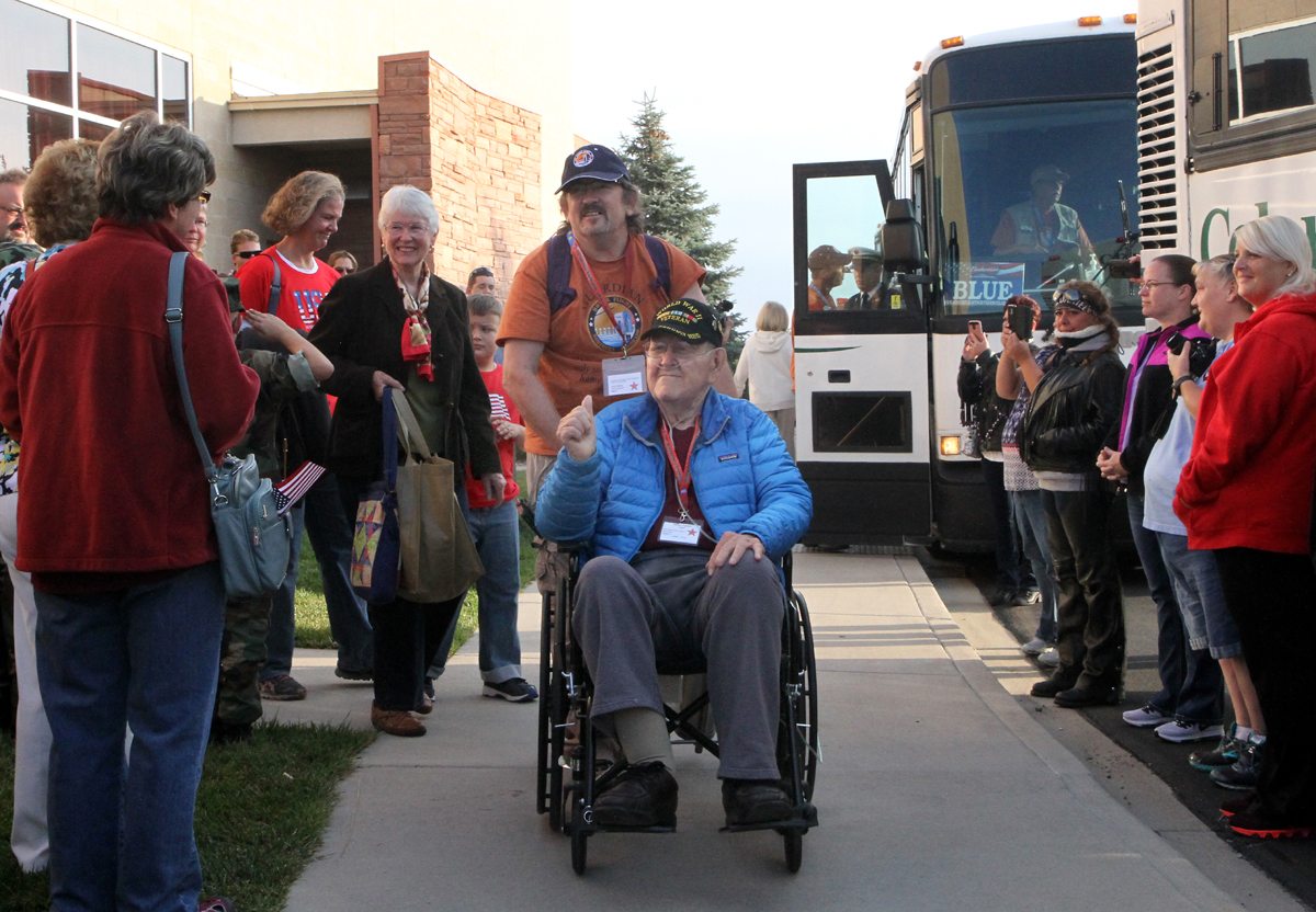 WWII Pfc. Jim Ingram, pushed by Sgt. John Darcy, gives the crowd a thumbs up as he gets ready to load the bus for the Honor Flight Northern Colorado trip on Sept. 17-18, 2017.