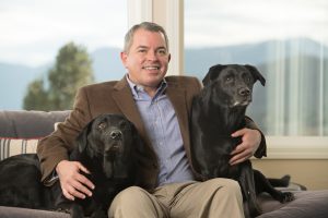 President and CEO Joel Yuhas sits with his two black labs