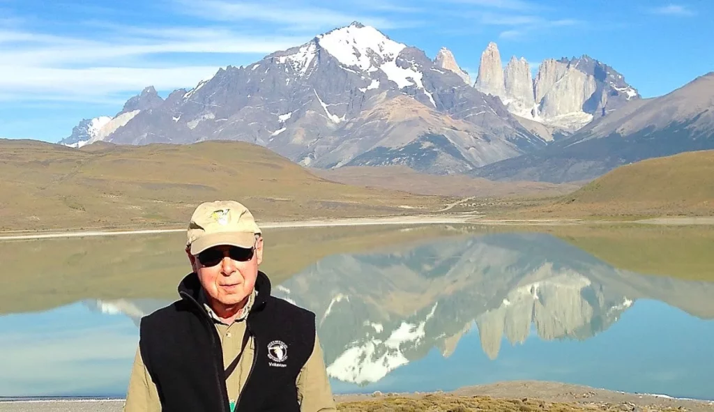 Mike Bloom stands in front of a lake and mountains in Patagonia in 2015. By asking the question, what is palliative care, he received a great deal of support during a serious illness.