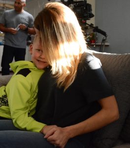 Melinda Ray is shown with her younger son, Kieran, and Jeff Bramstedt in the background.