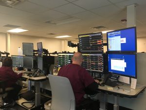 A man sits in front of a bank of four computers to monitor UCHealh's Virtual Health Center.